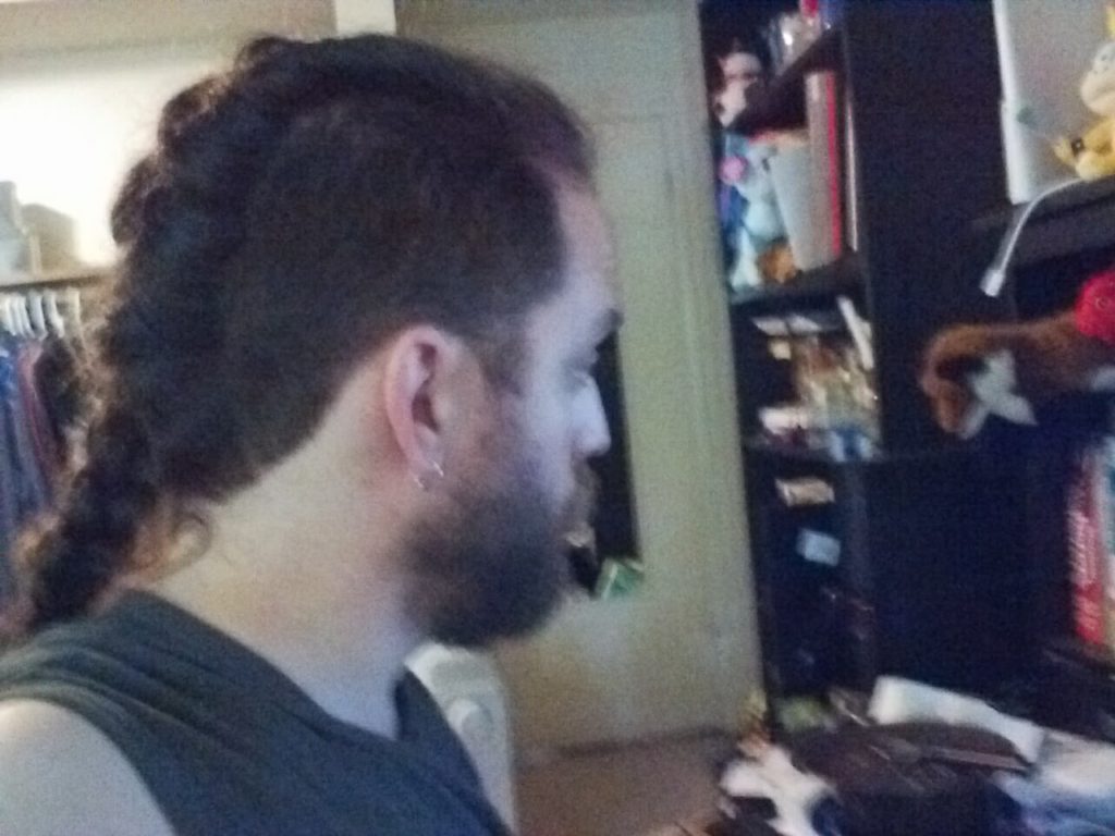 Ian facing to the right,showing his long hair braided along his mohawk line.