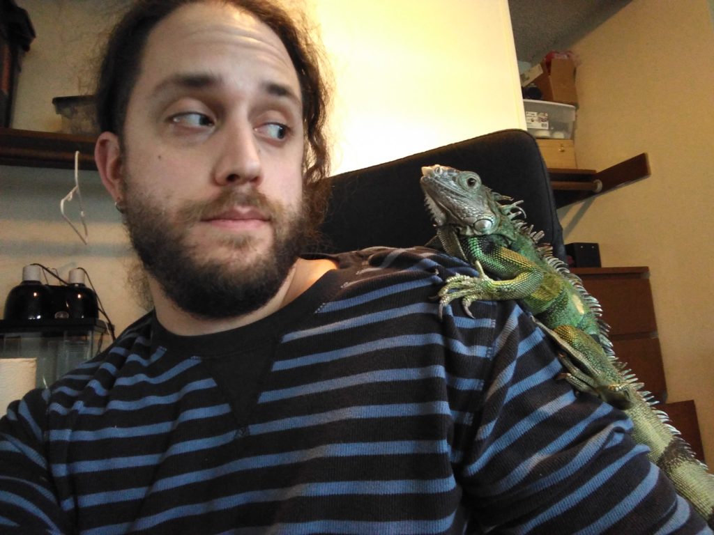 An image fo the author giving the doubtful side eye to Jabberwocky the iguana, who is perched on his shoulder.