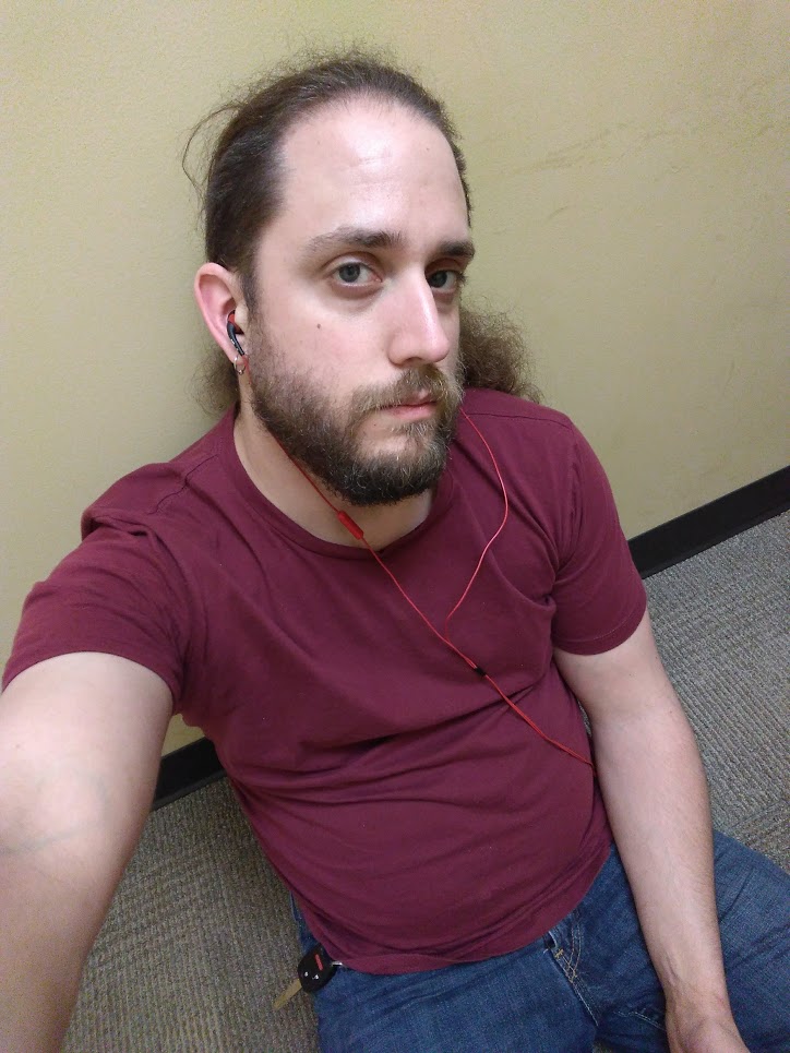 Picture of the author sitting on the floor, back against a wall, looking up into the camera with bags under his eyes.