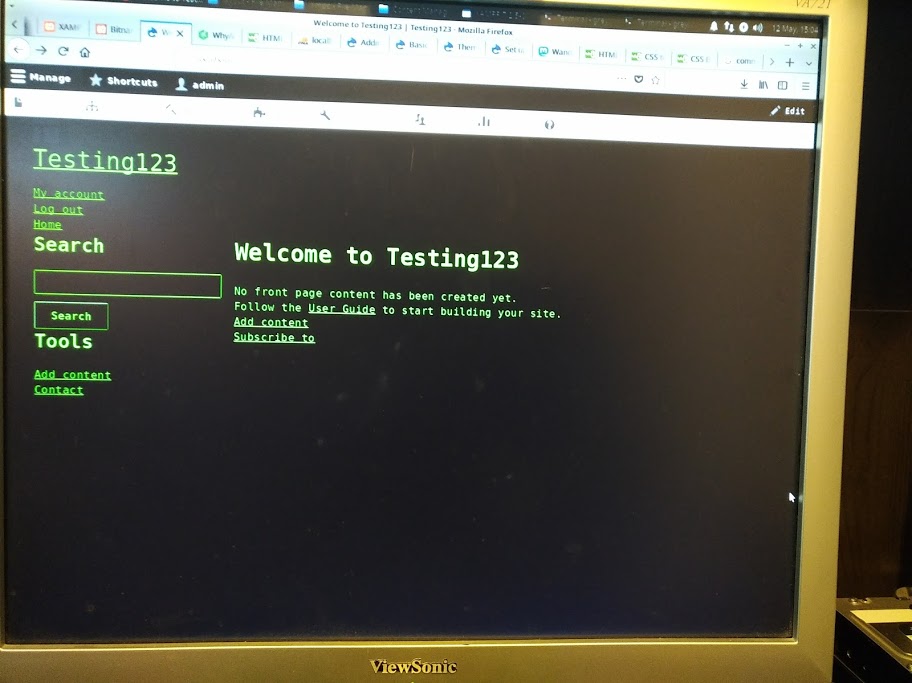 Photo of a monitor displaying a green-on-black website with monospaced font. The headline reads "Welcome to Testing123."