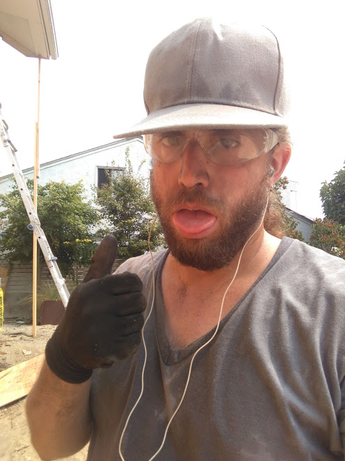 The author, with work gloves, a baseball cap, and protective glasses, giving a thumbs up while dirty, sweaty, and exhausted-looking to the point of sticking his tongue out.