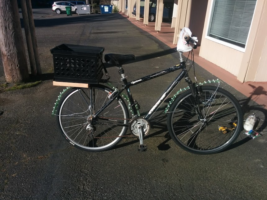 A bike with home-made fenders made of old soda bottles attached, as well as a milk crate attached as a basket.