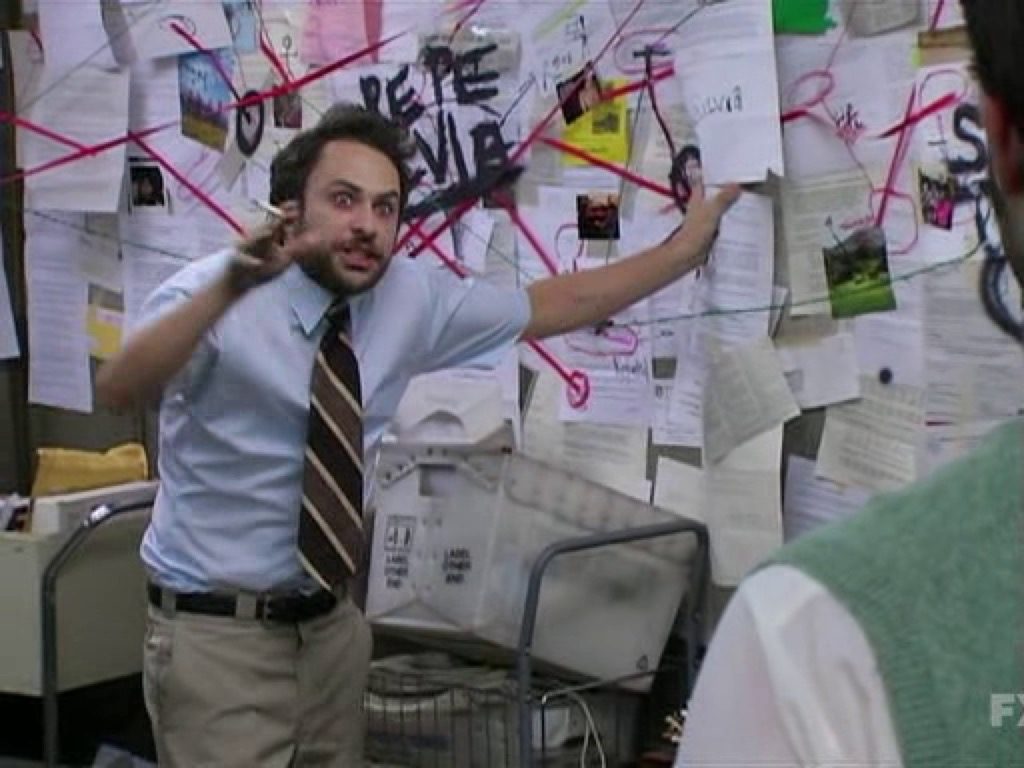 Charlie from It's Always Sunny in Philadeplhia gesturing wildly in front of a wall covered in pieces of paper connected by red lines in classic "conspiracy board" style.